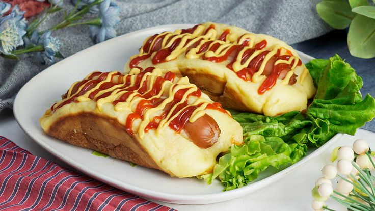 two hotdogs with ketchup and lettuce on a plate