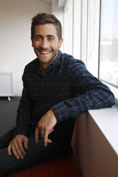 a smiling man sitting on the edge of a window sill in an office building