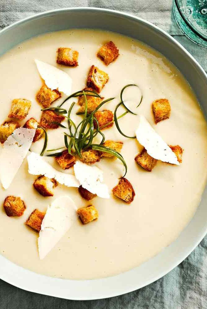 a bowl of soup with croutons and garnishes on the side