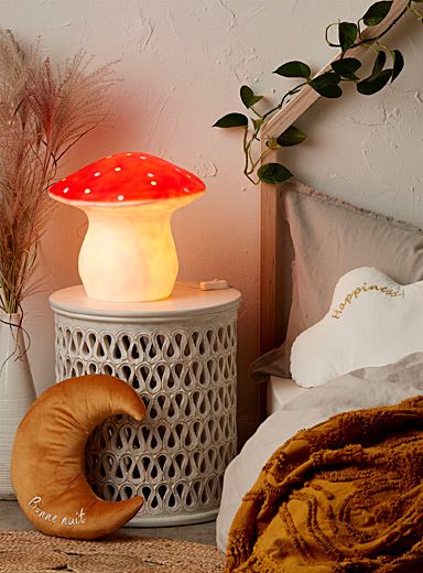 a mushroom shaped lamp sitting on top of a table next to a bed with pillows