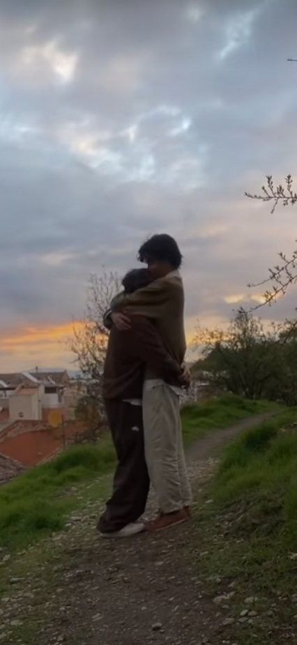 two people embracing each other on a hill