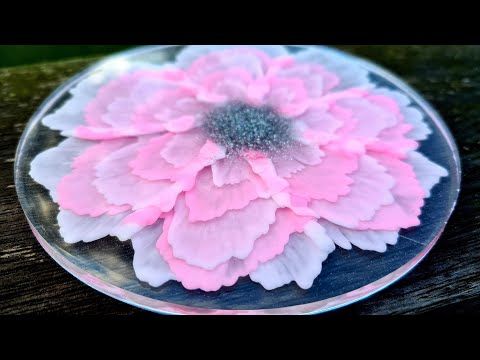 a pink and white flower sitting on top of a glass plate