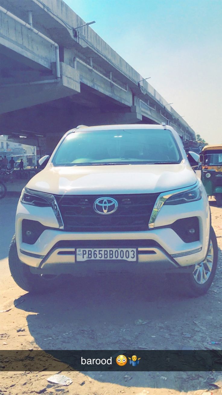 a white suv parked in front of an overpass