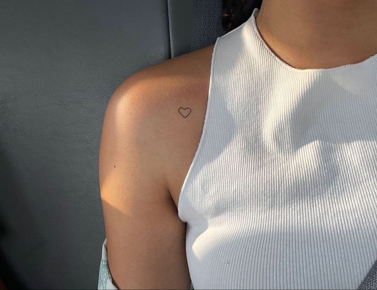 a woman with a small heart tattoo on her left shoulder