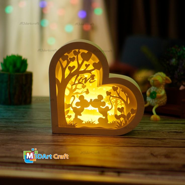 an illuminated heart shaped box with mickey and minnie mouse silhouettes on it