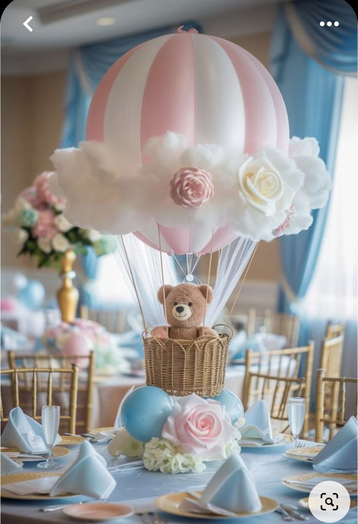 a teddy bear sitting in a basket on top of a table with flowers and balloons