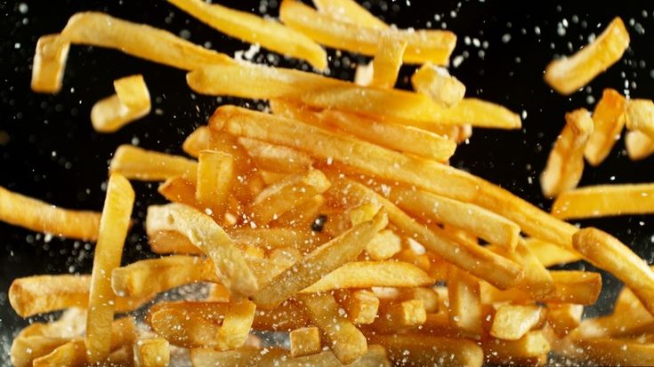 french fries being fried in oil on a black surface