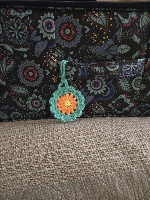 a crocheted keychain sitting on top of a couch next to a purse