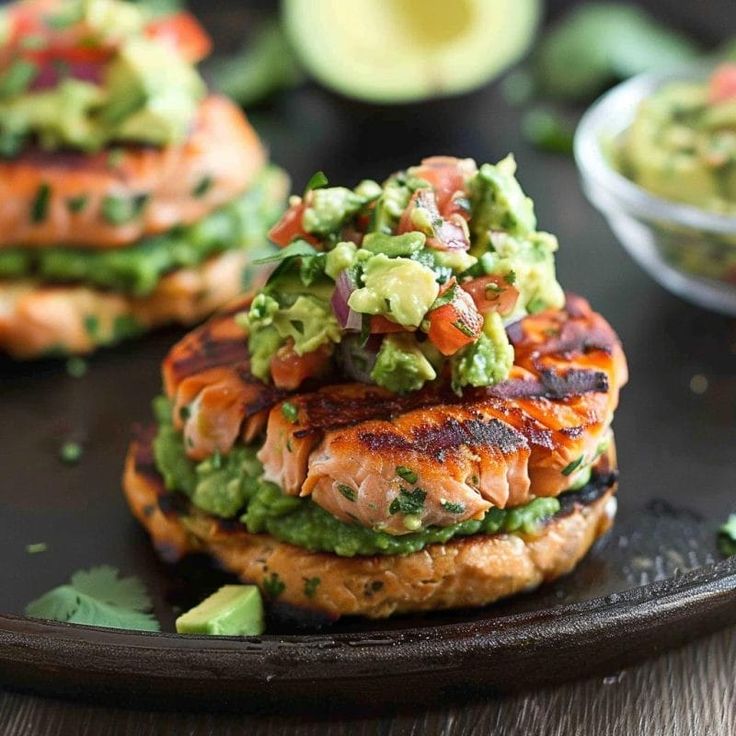 salmon burgers with guacamole and avocado on a black plate