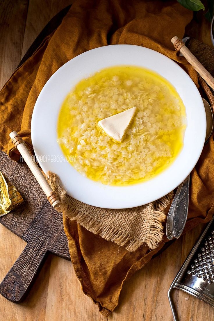 a white bowl filled with soup and topped with a piece of cheese on top of it