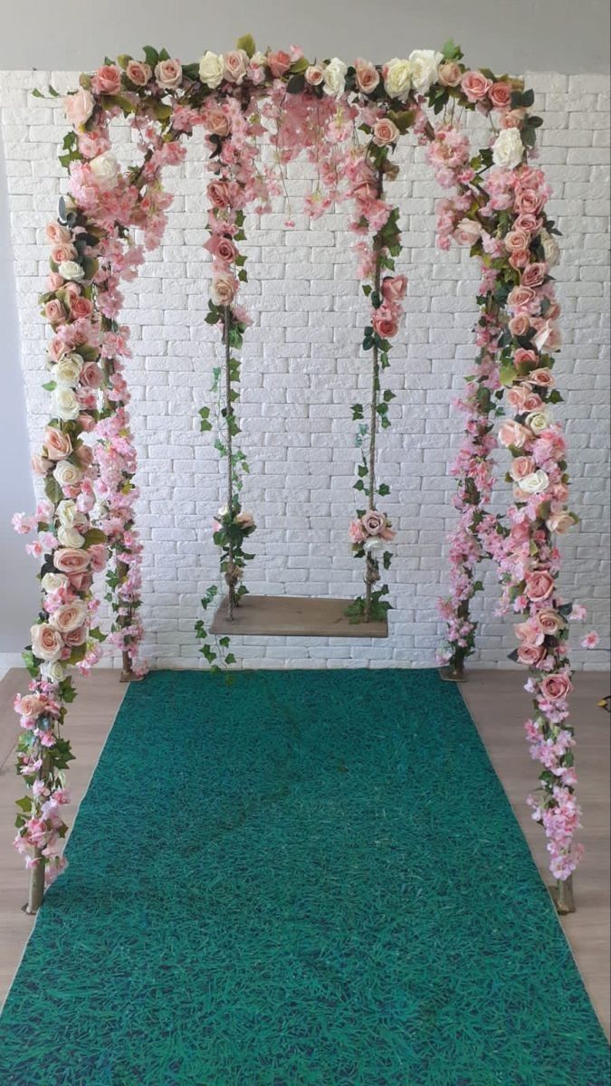 an outdoor wedding ceremony with pink and white flowers on the arch, green carpet and brick wall