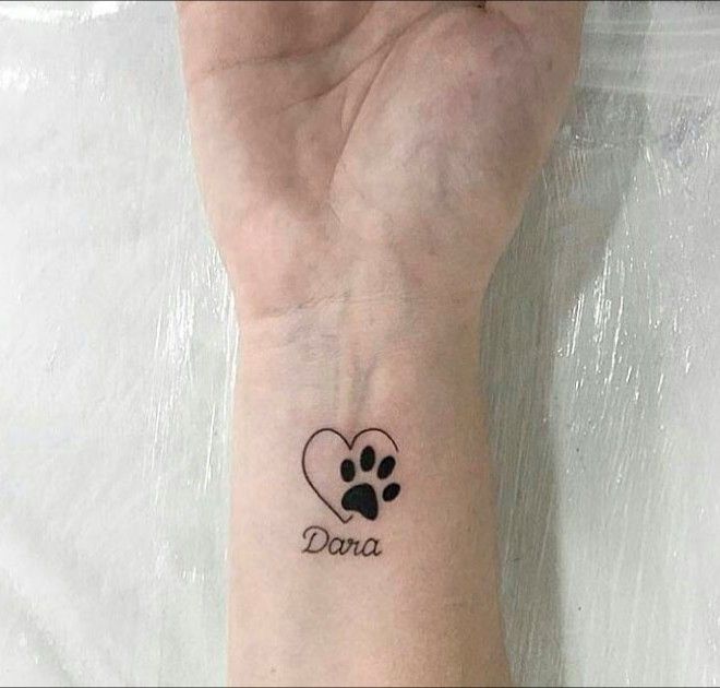 a woman's wrist with a dog paw and heart tattoo on her left arm