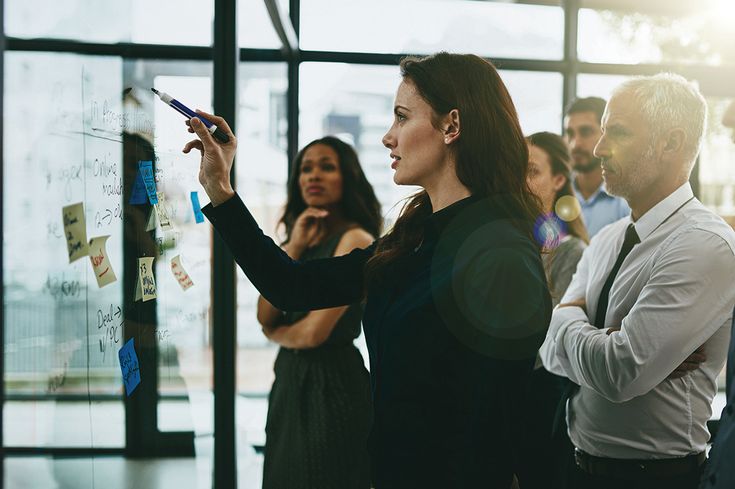 a group of people standing in front of a glass wall with sticky notes on it