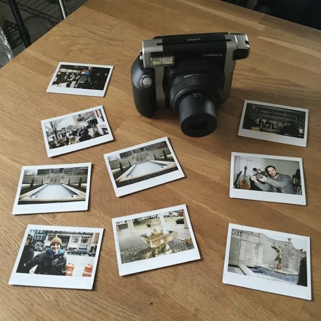 an old fashioned camera sitting on top of a wooden table with polaroid photos around it