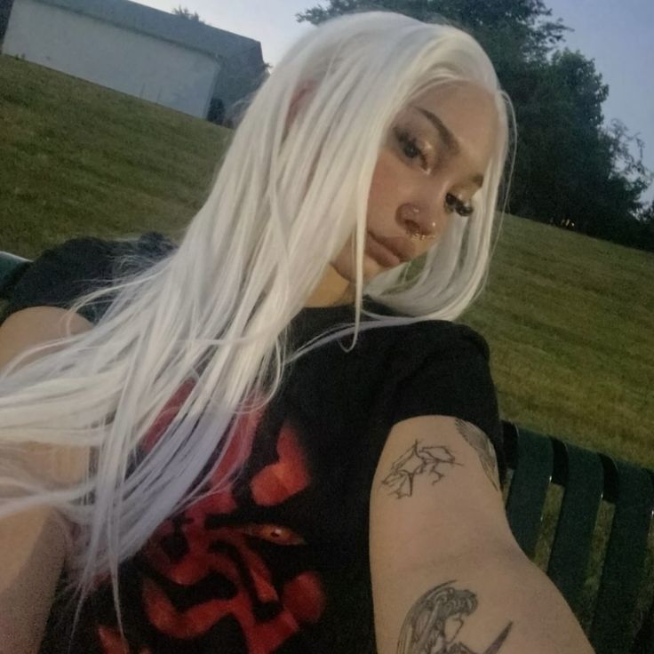 a woman with long white hair and tattoos on her arm