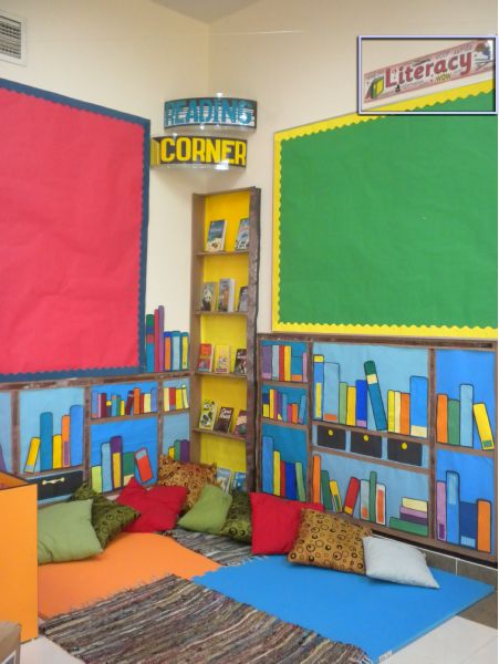 a room with colorful bookshelves and pillows on the floor in front of it