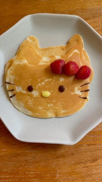 a plate topped with pancakes covered in butter and strawberries on top of a wooden table