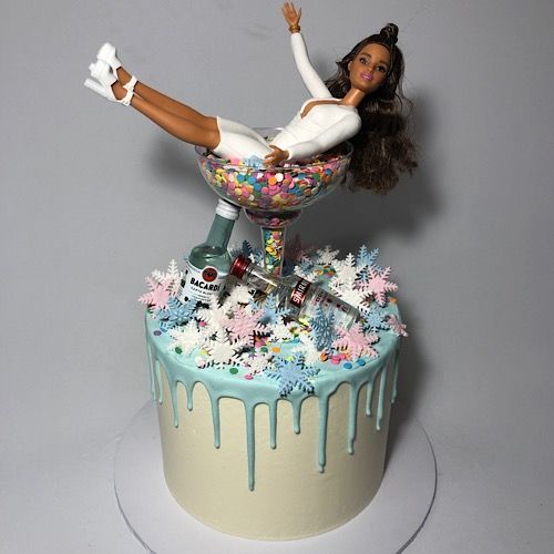 a cake with a barbie doll sitting on top of it and sprinkles