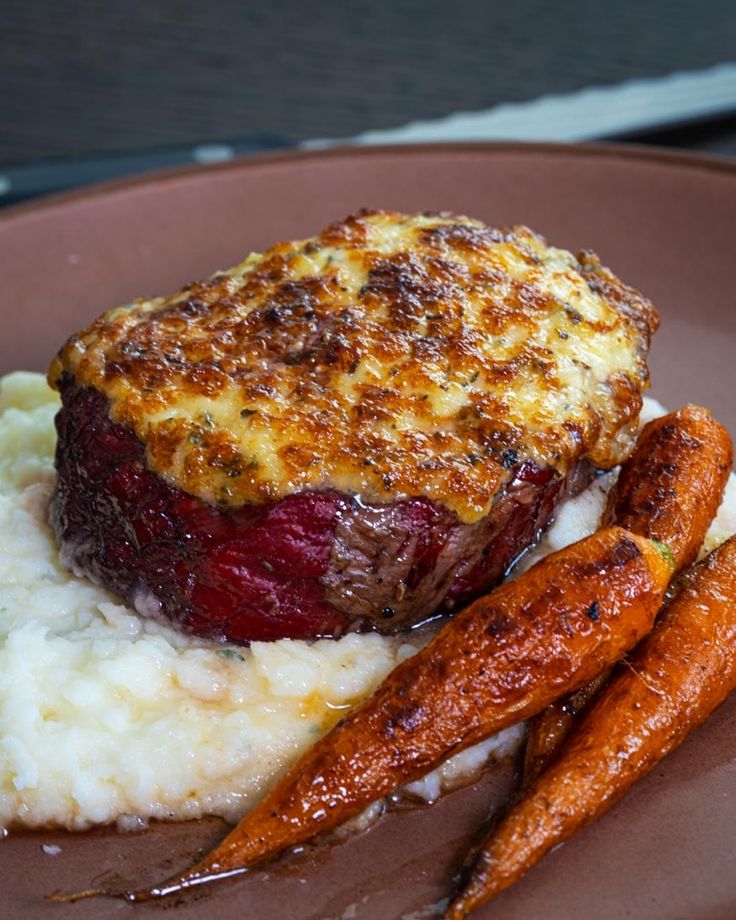 a plate with mashed potatoes, carrots and meatloaf on it is shown