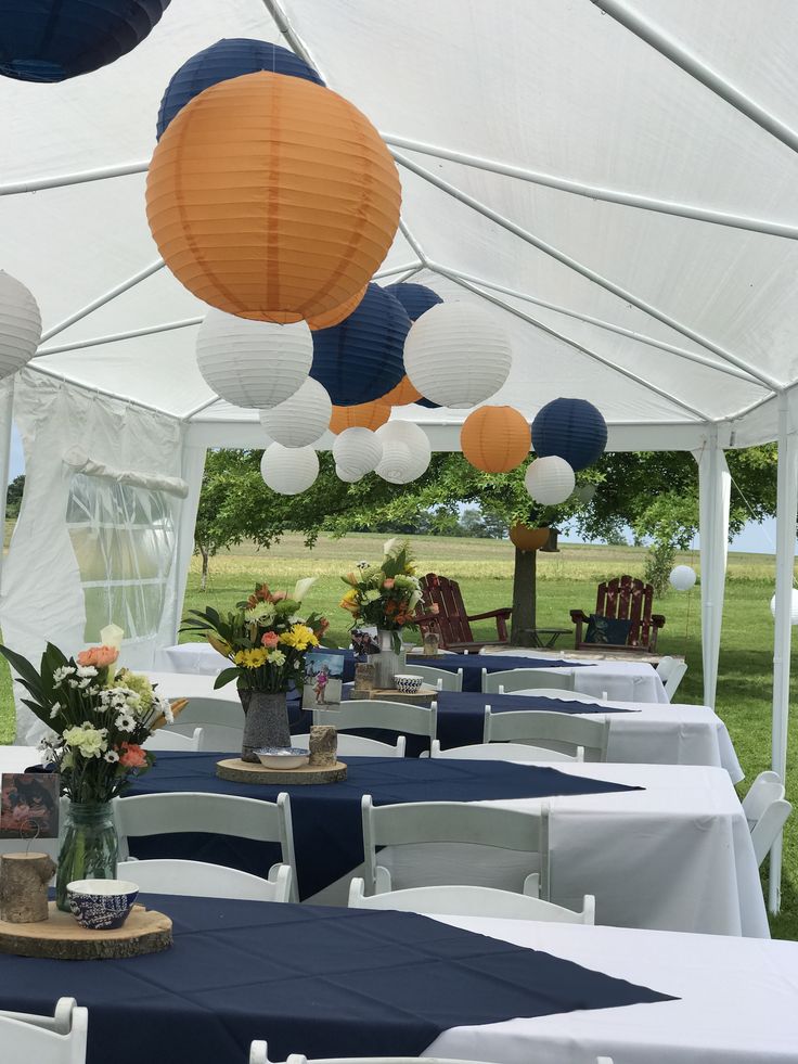 tables and chairs are set up under white tents with blue tablecloths on them