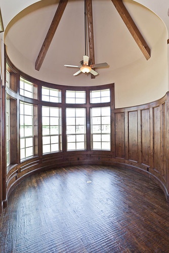 an empty room with wood paneling and a ceiling fan