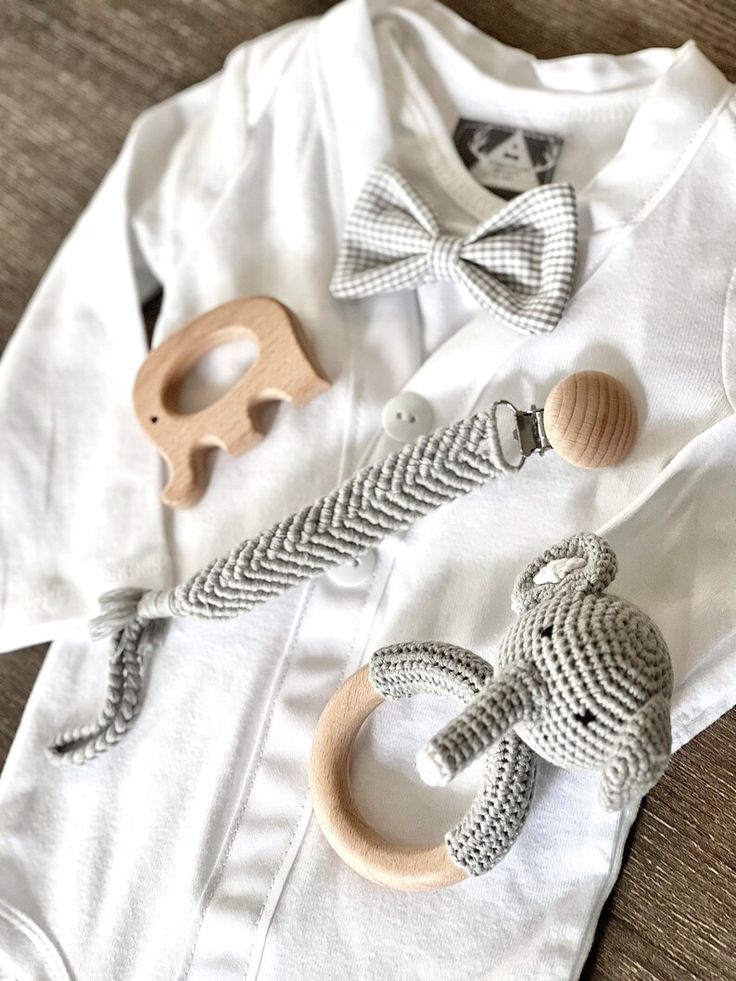 a baby's white shirt with wooden toys on it and some other items laying next to it