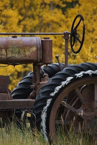 an old rusty tractor sitting in the grass