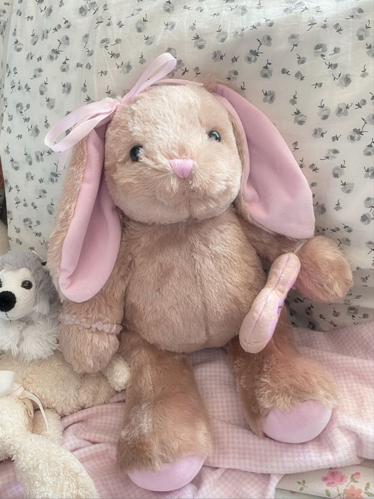 a stuffed rabbit sitting on top of a bed next to two other stuffed animal animals