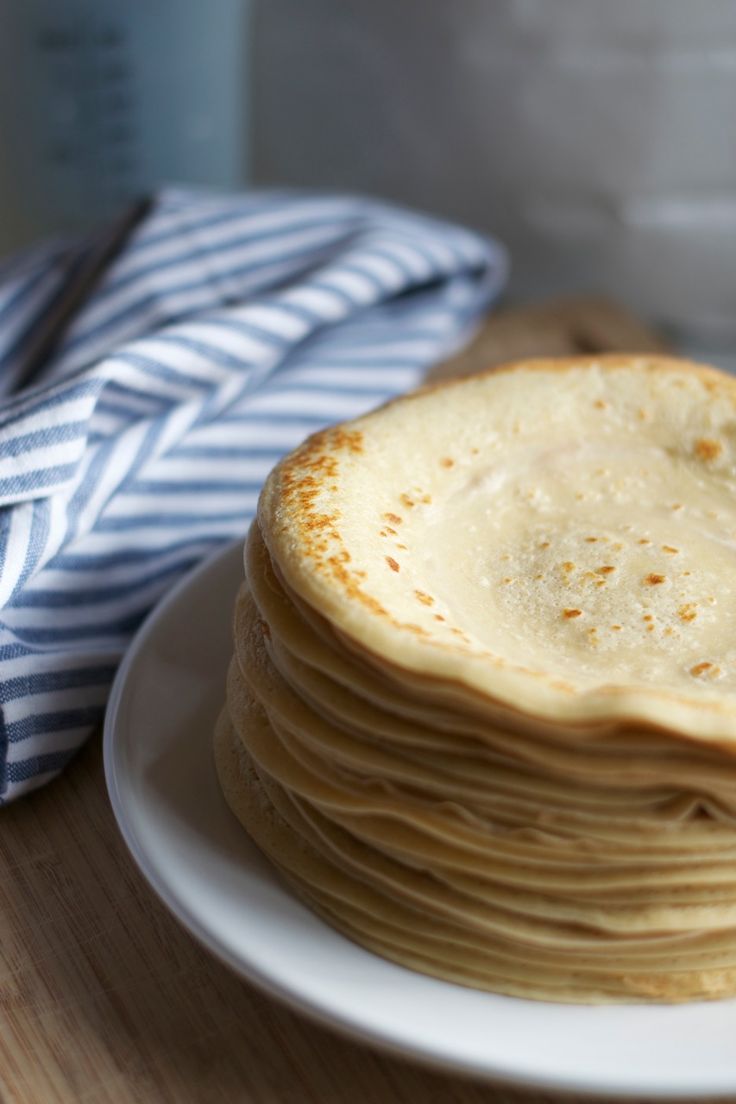 a stack of pancakes sitting on top of a white plate next to a blue and white napkin