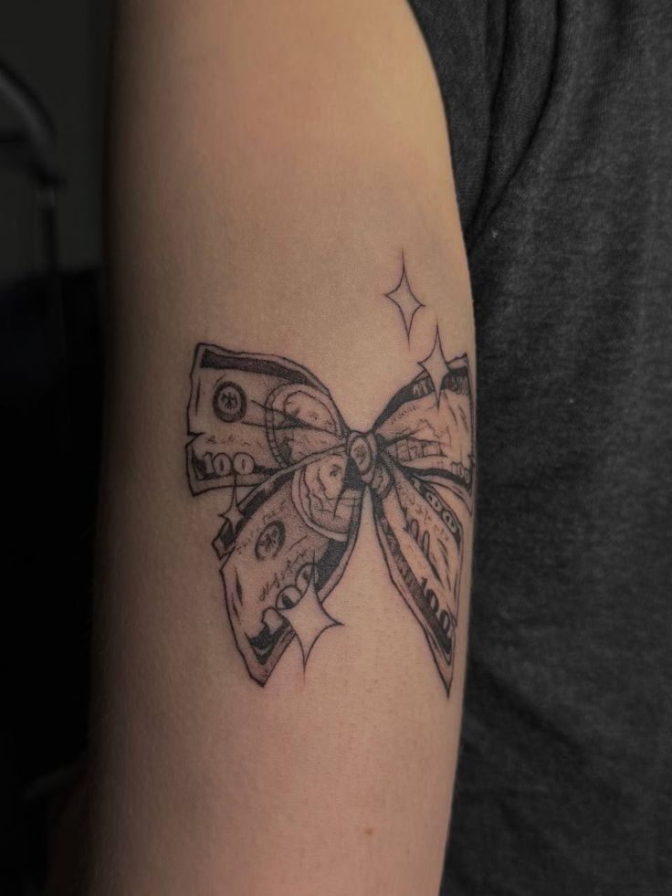 a woman's arm with a bow and money tattoo on the left side of her arm