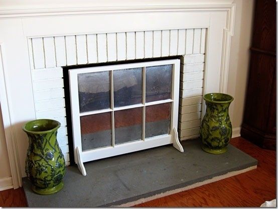 a fireplace with two vases sitting on the floor in front of it and a window