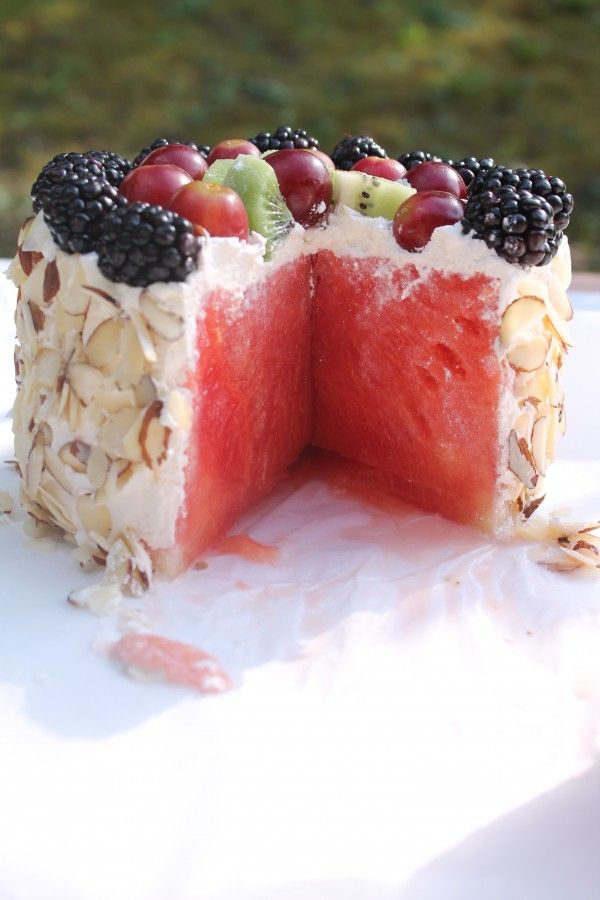 a watermelon cake with blackberries, kiwis and grapes on top