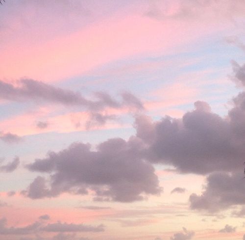 an airplane is flying in the sky at sunset or dawn with clouds and blue, pink, and purple colors