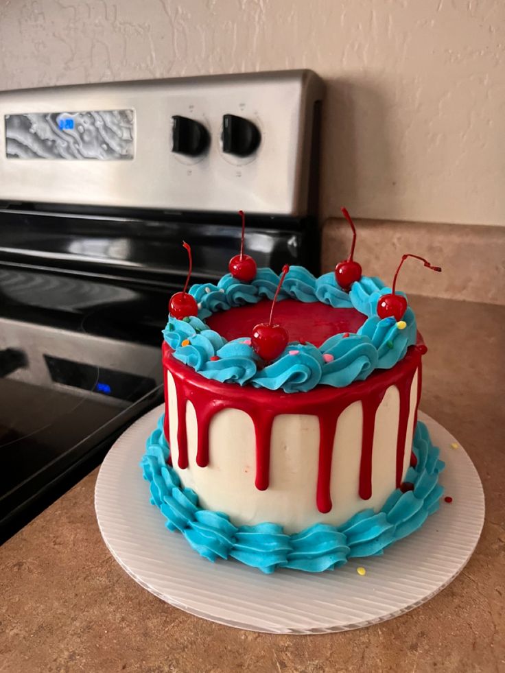 a cake sitting on top of a counter next to an oven in a kitchen with red, white and blue icing