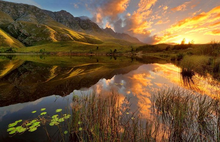 the sun is setting over a mountain lake