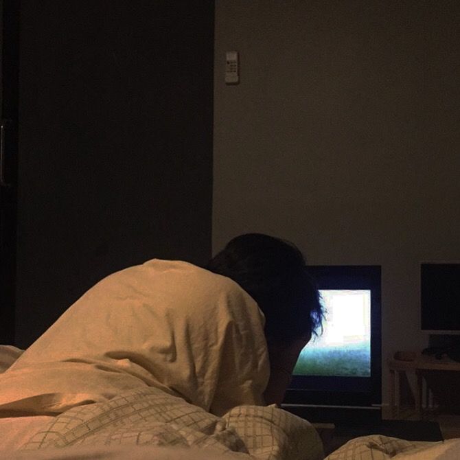 a man laying in bed watching television at night