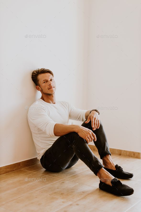 a man sitting on the floor in front of a white wall - stock photo - images