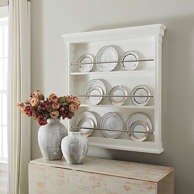 two vases with flowers sit on a dresser in front of a white china cabinet