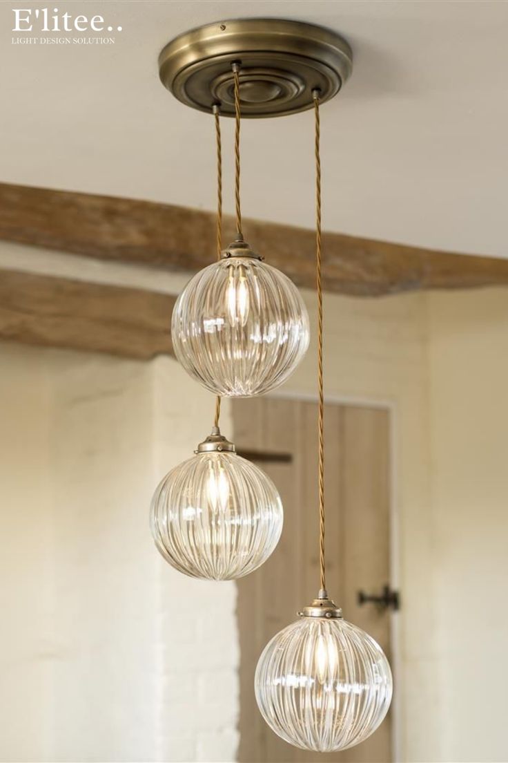 three clear glass globes hanging from a ceiling fixture in a home kitchen or dining room