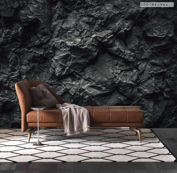 a couch sitting on top of a white rug in front of a black rock wall