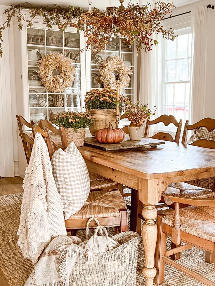 a wooden table topped with lots of potted plants next to a basket filled with pumpkins