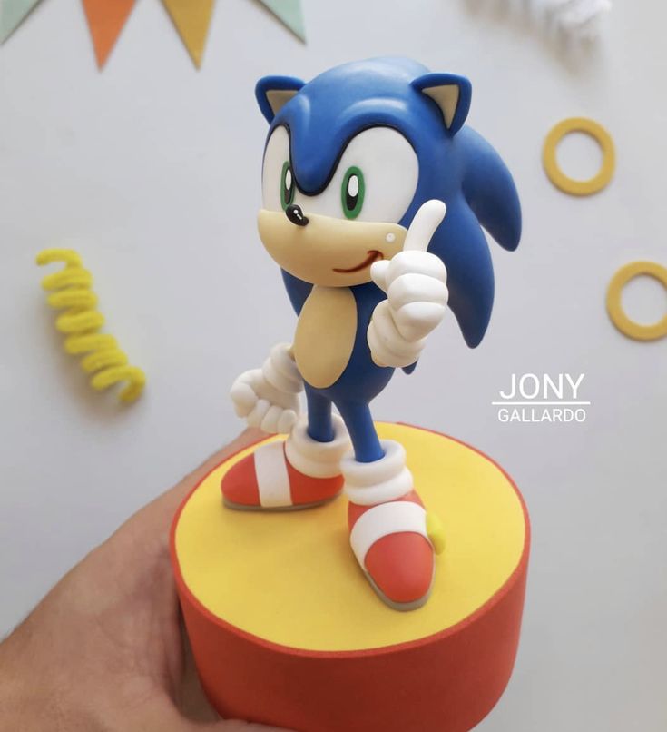 a person holding a toy sonic the hedge on top of a round table with confetti and streamers in the background