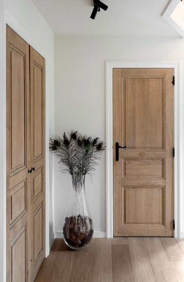 a vase filled with flowers sitting on top of a wooden floor next to two doors