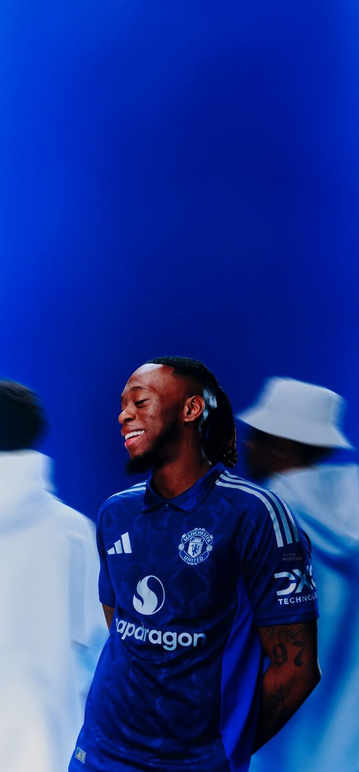 a man with dreadlocks standing in front of a blue background wearing a soccer uniform