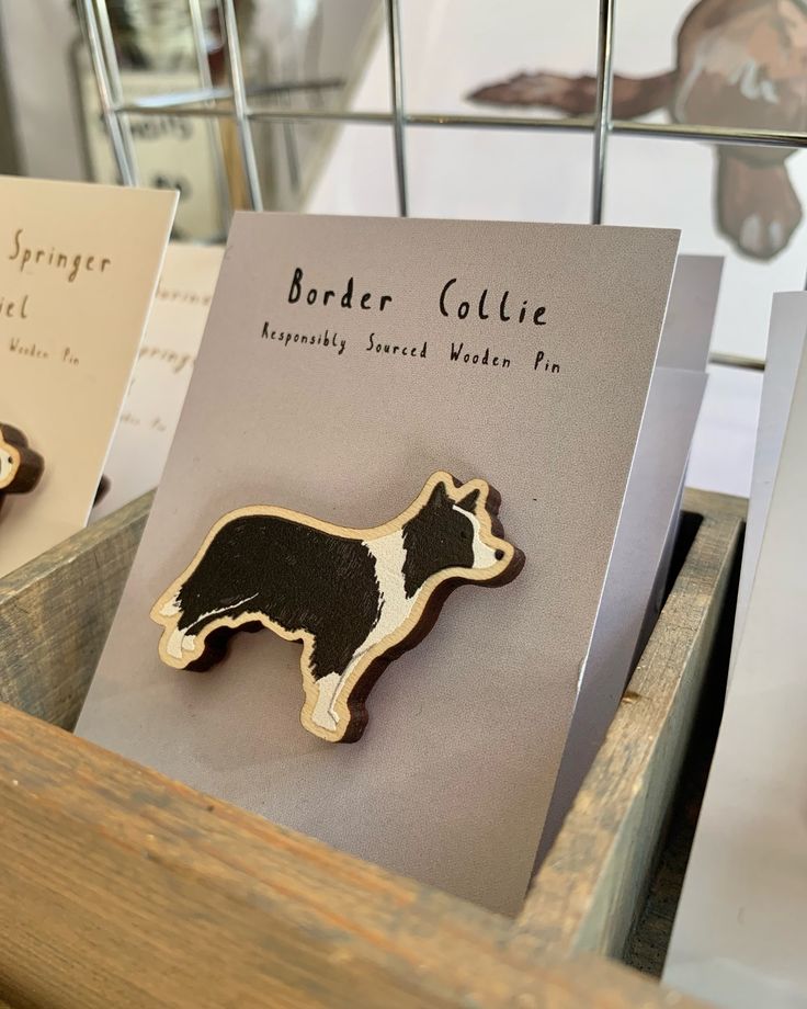 two wooden brooches sitting on top of a table next to cards with animals