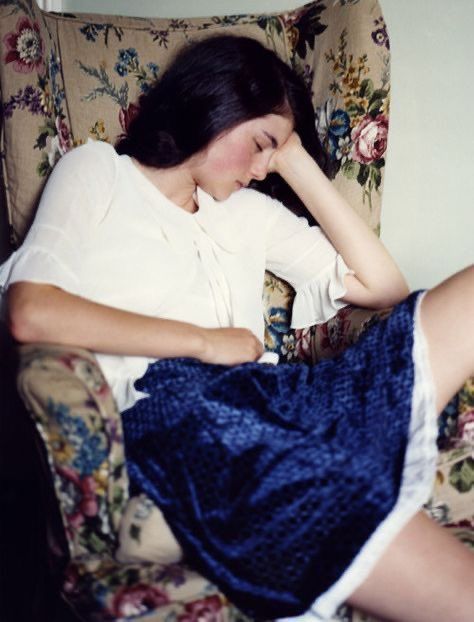 a woman is sitting in a chair with her hand on her face and eyes closed