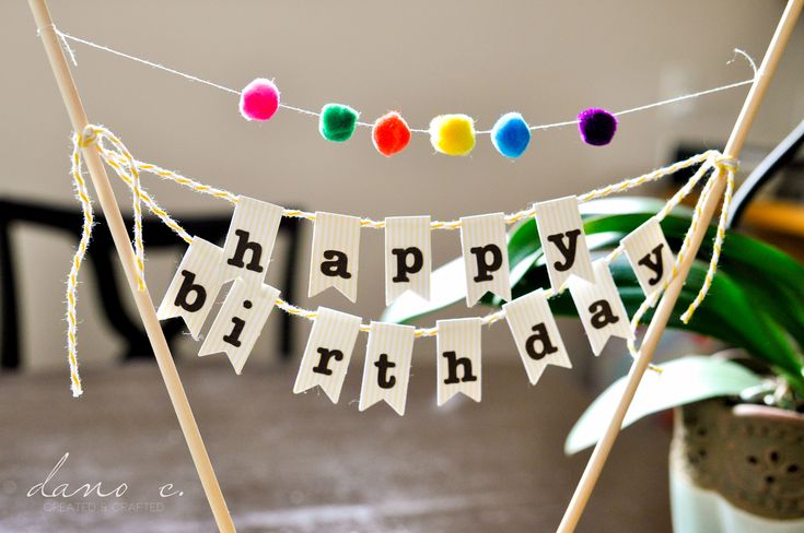 a happy birthday banner is hanging on a table with potted plant in the background