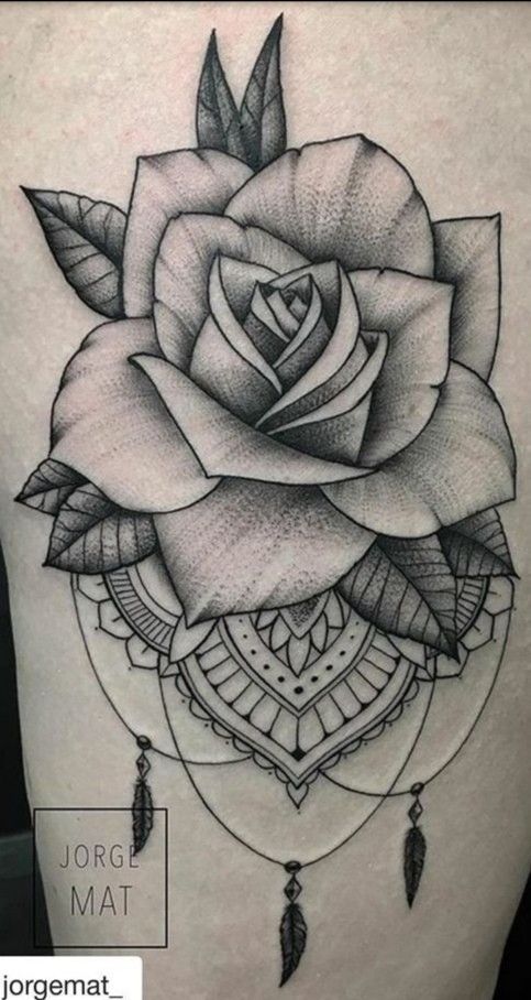 a black and white rose tattoo on the back of a woman's stomach, with feathers