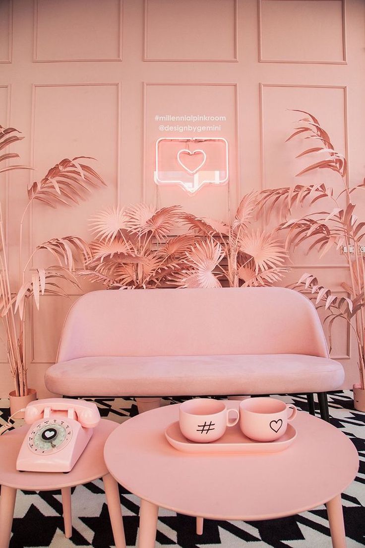 a pink couch and coffee table in front of a wall with palm leaves on it