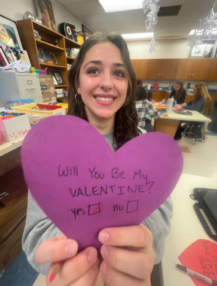 a woman holding up a purple heart with writing on it